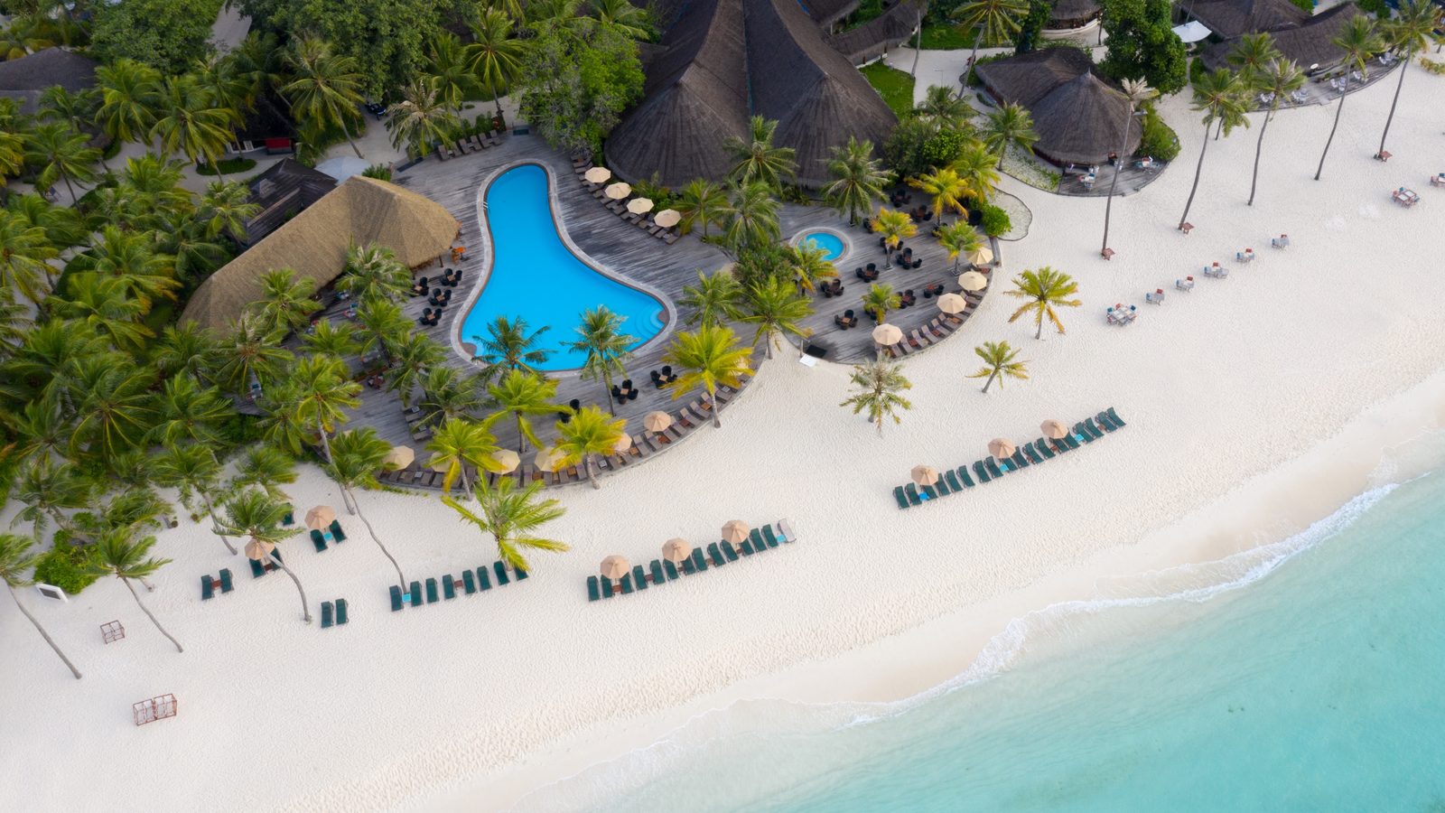 Aerial view of a Maldives resort pool and beach loungers