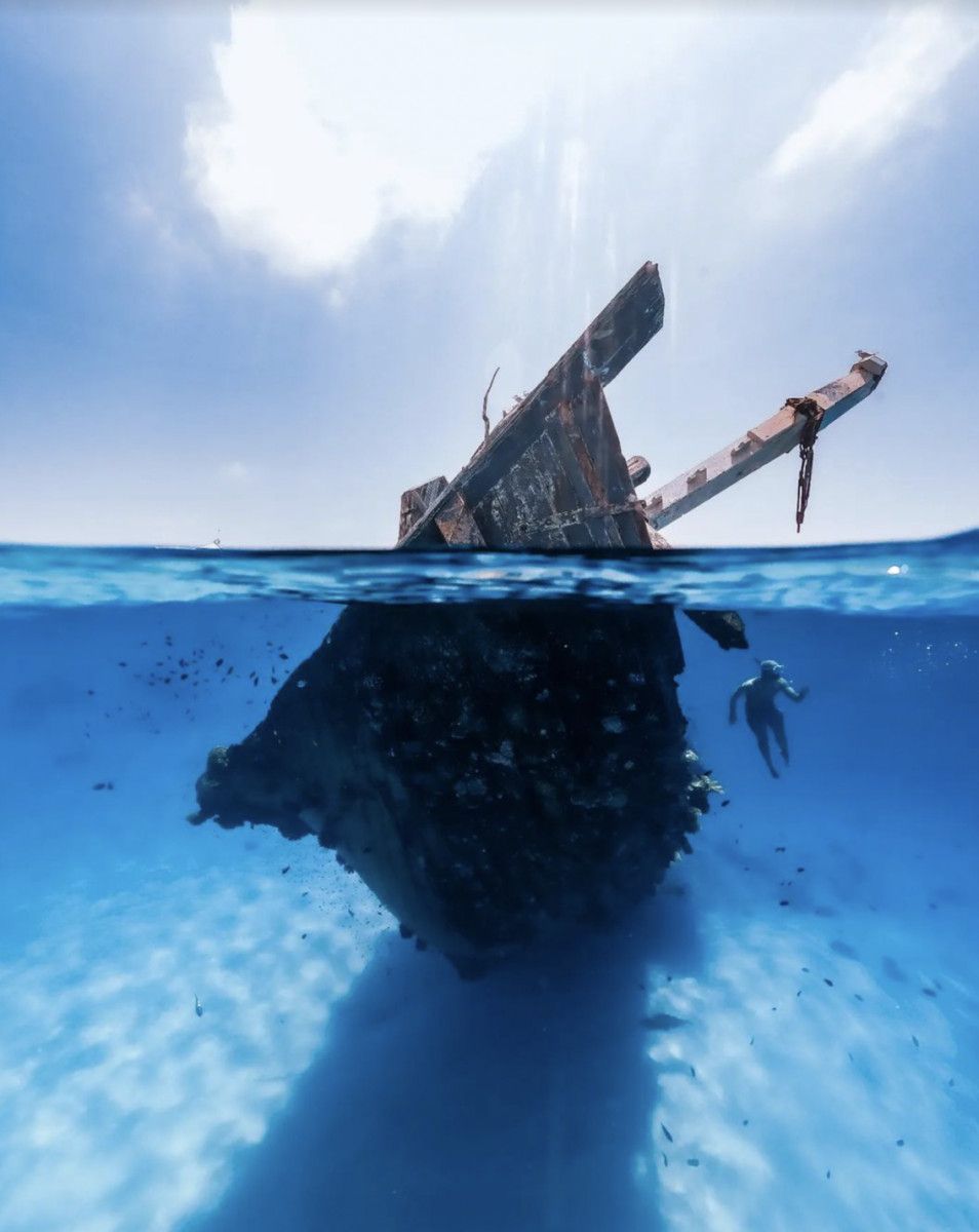 Diver exploring a shipwreck, half-underwater split shot